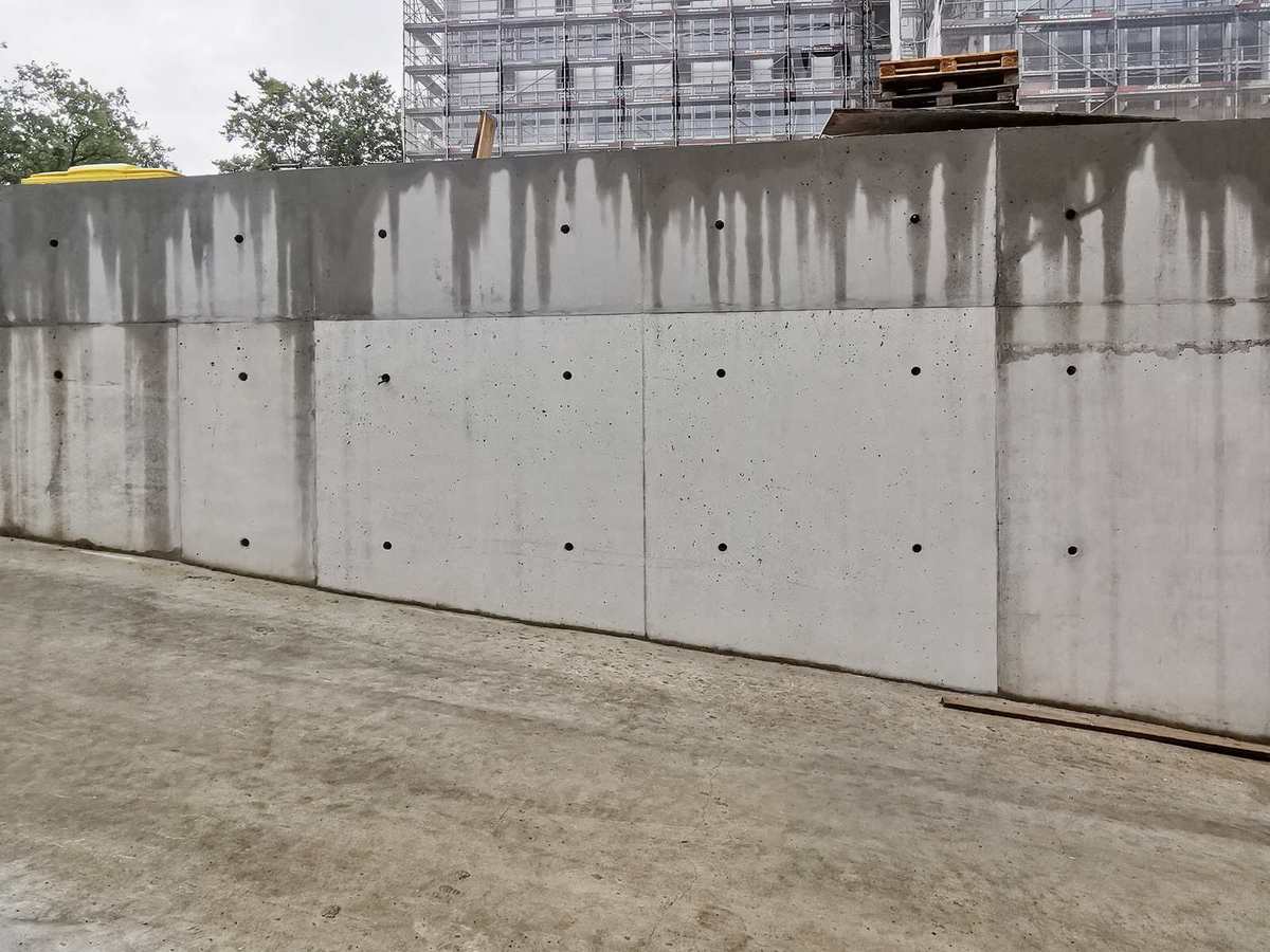 Sichtbeton-Schutz: geschützte Fläche bleibt sauber, ungeschützte Betonkrone zeigt Wasserfahnen