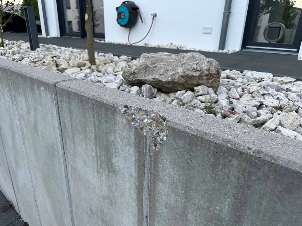 Ausbruch an einer Sichtbeton-Stele mit offenem Kiesbett